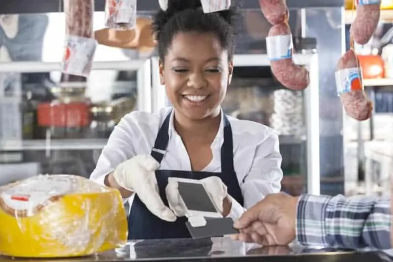 Black female butcher accepts credit card on mobile phone
