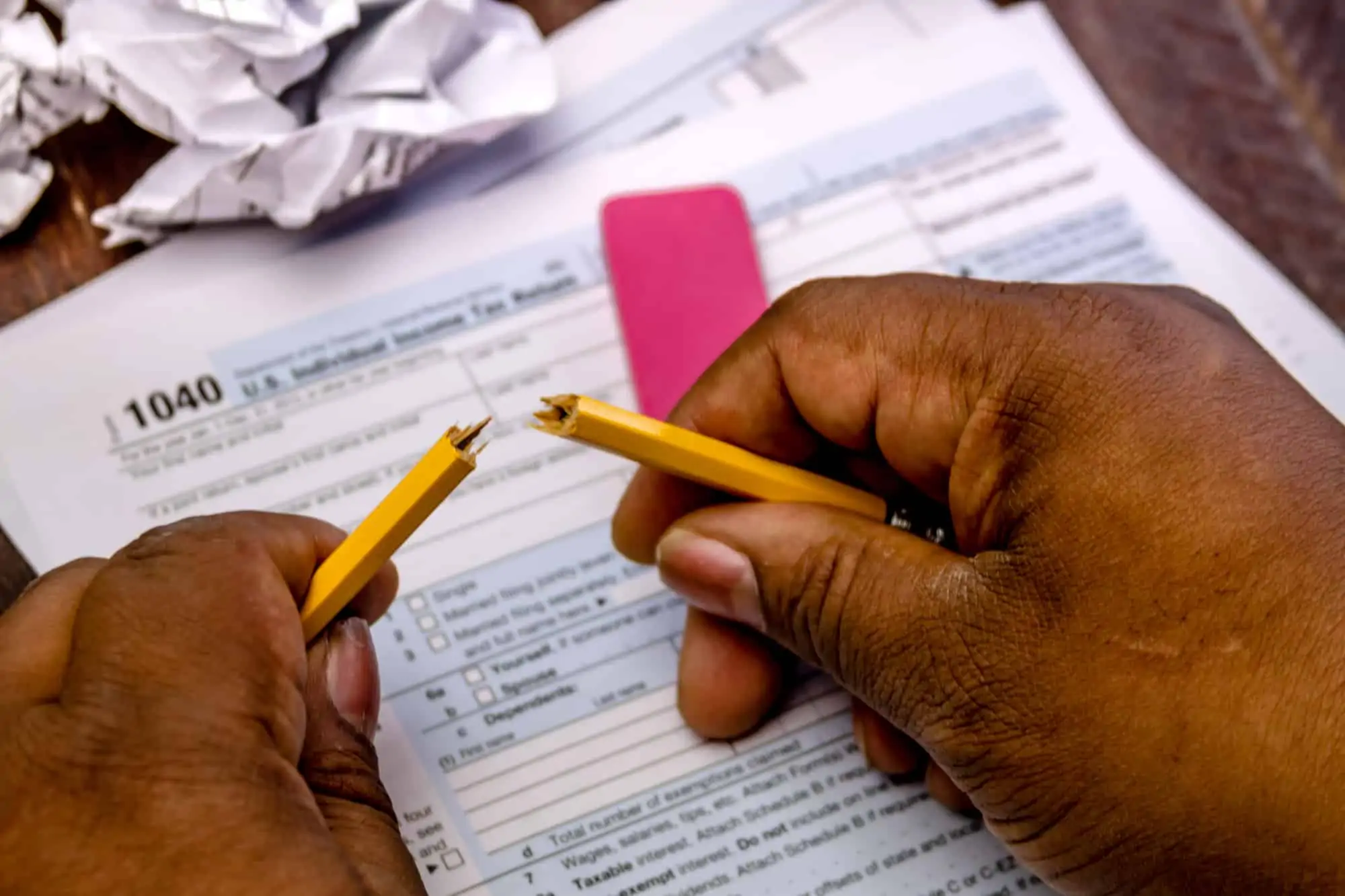 Black male hands holding broken pencil with tax form 1040 for bartering income