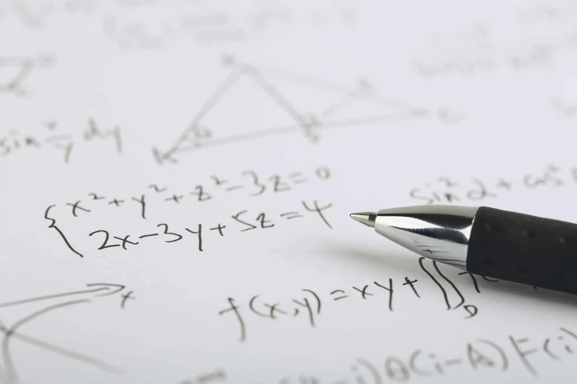 Calculating net income using complex math formulas on paper with a black ceramic ball pen.