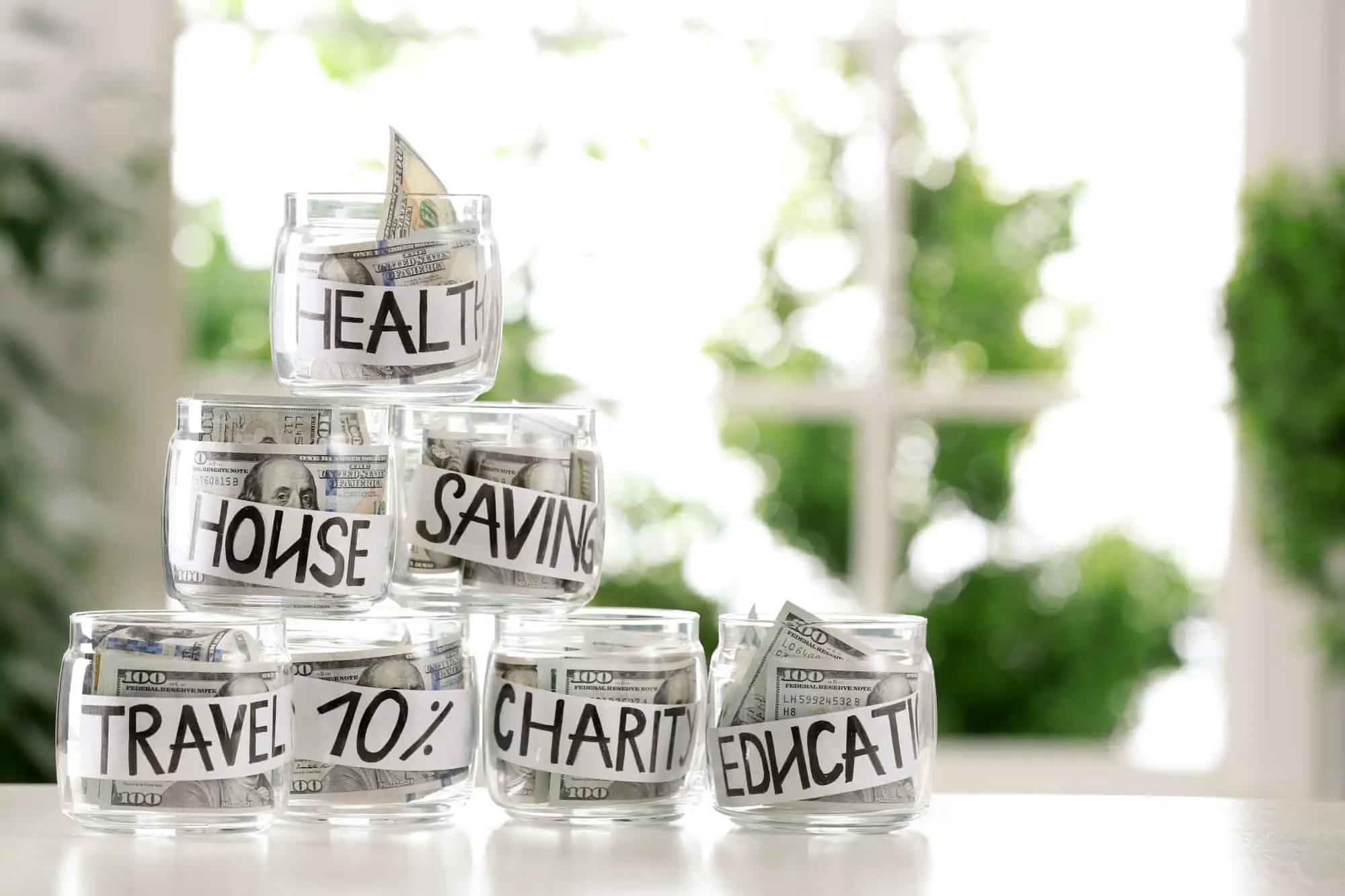Jars of hundred dollar bills for savings goals and maintaining separate bank accounts.